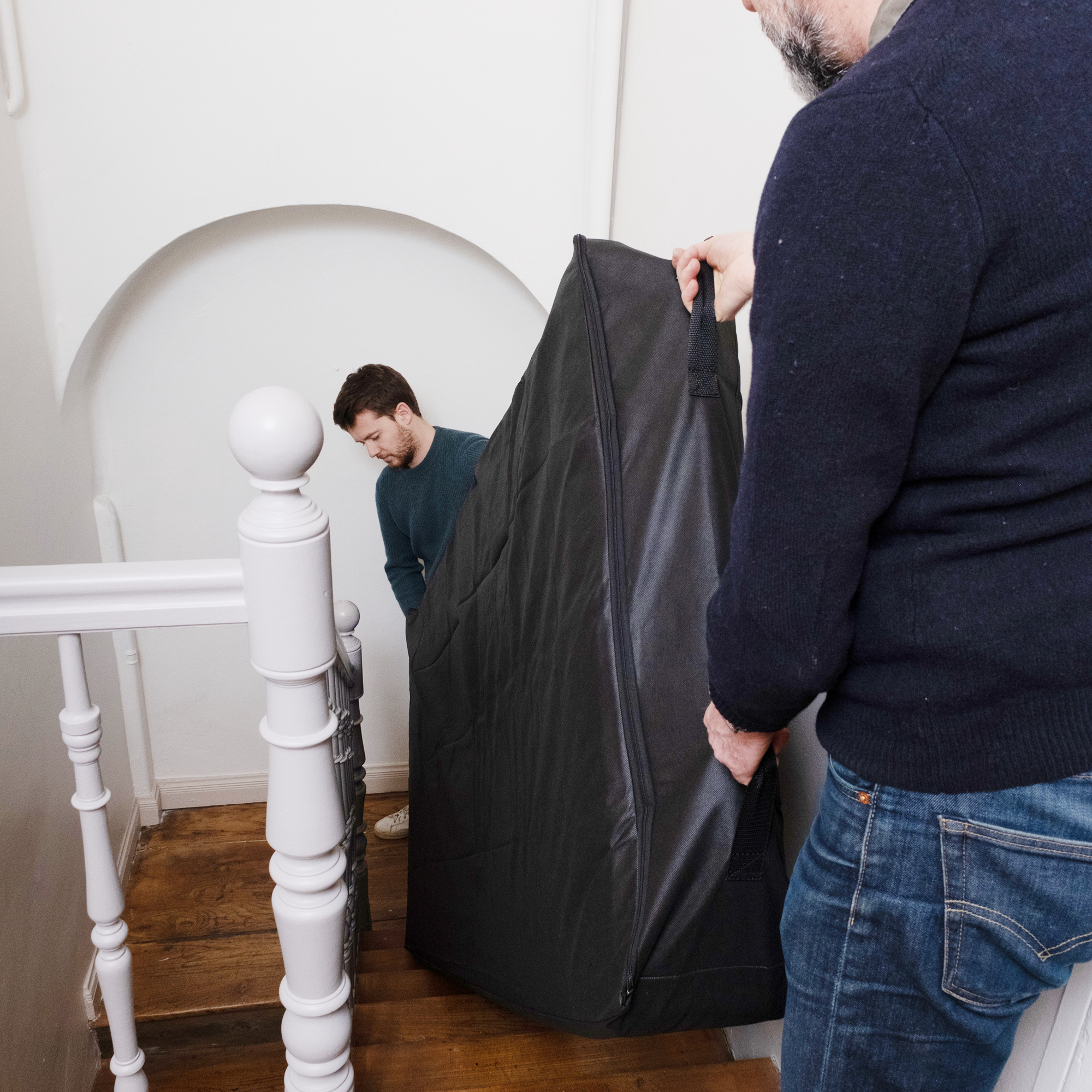 deux personnes qui transportent un matelas adulte dans un escalier avec une housse matelas très solide